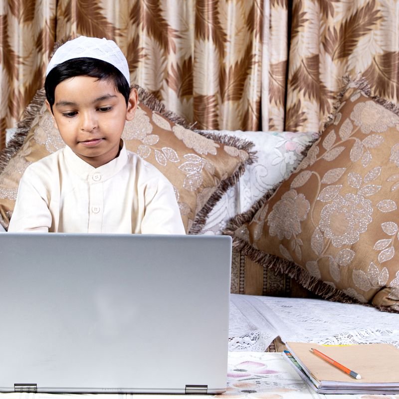 Boy learning Quran online on a laptop at home